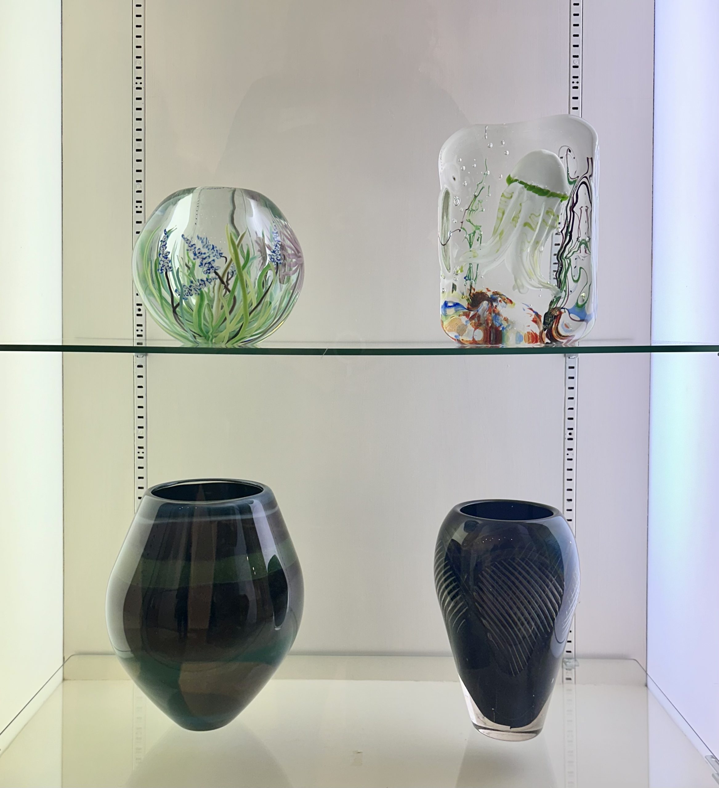Four glass artworks in a case at the Bergstrom-Mahler