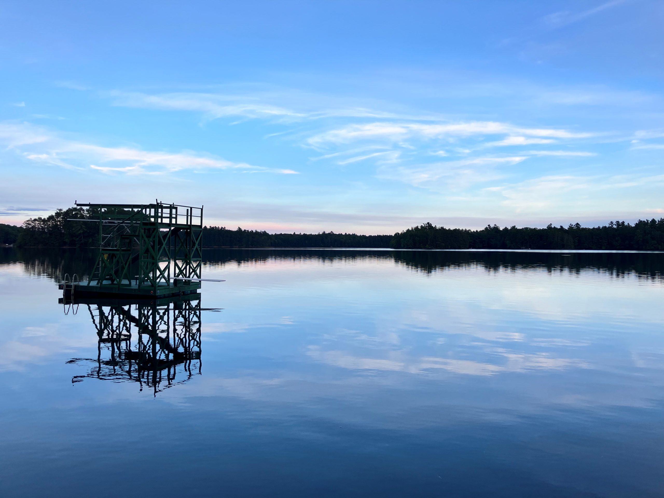 This image shows the sun setting on a still lake in Northern Wisconsin