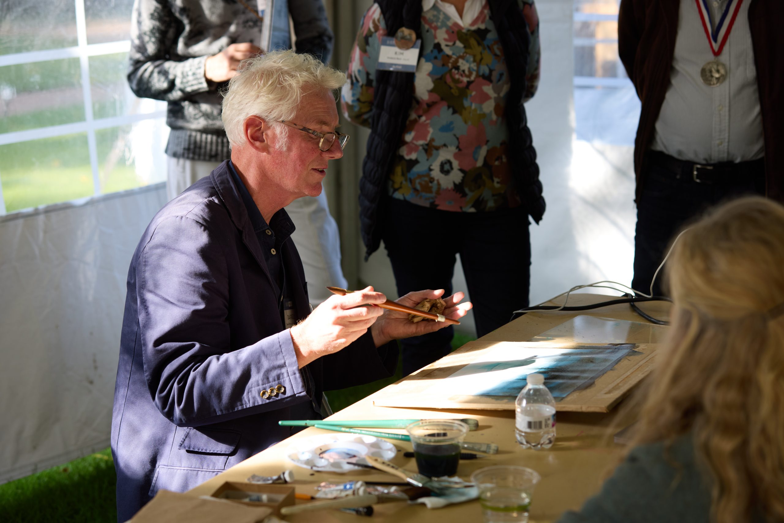 This image shows an artist painting in front of a crowd