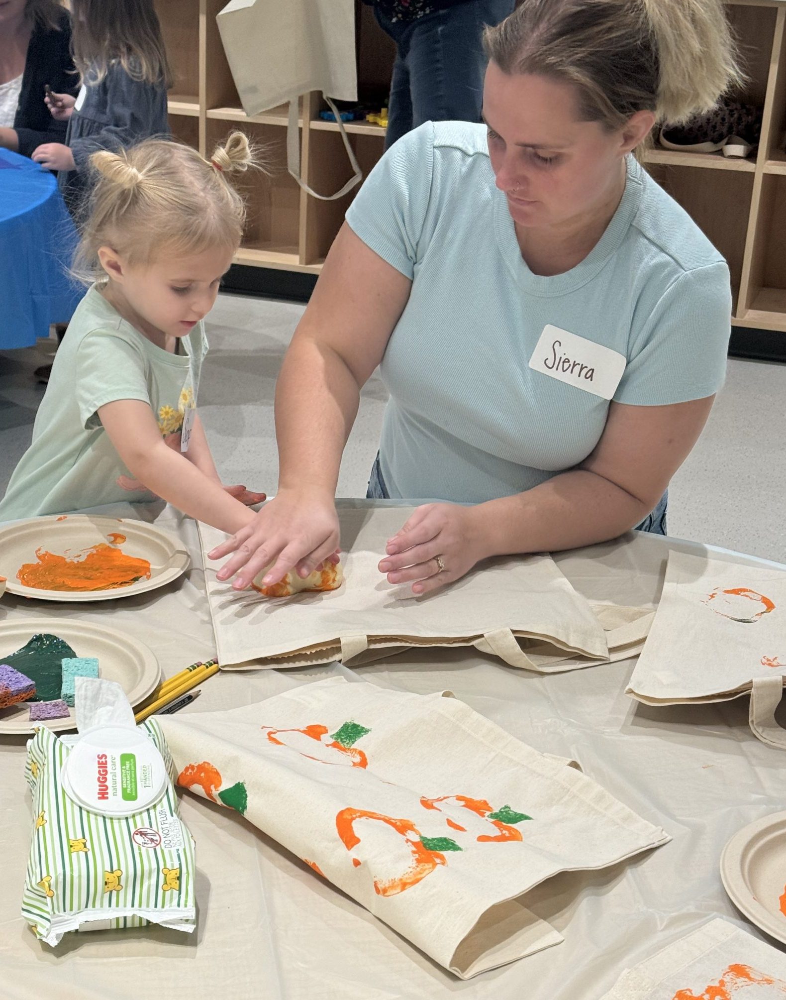 a woman and a child making a print of a pumpkin together