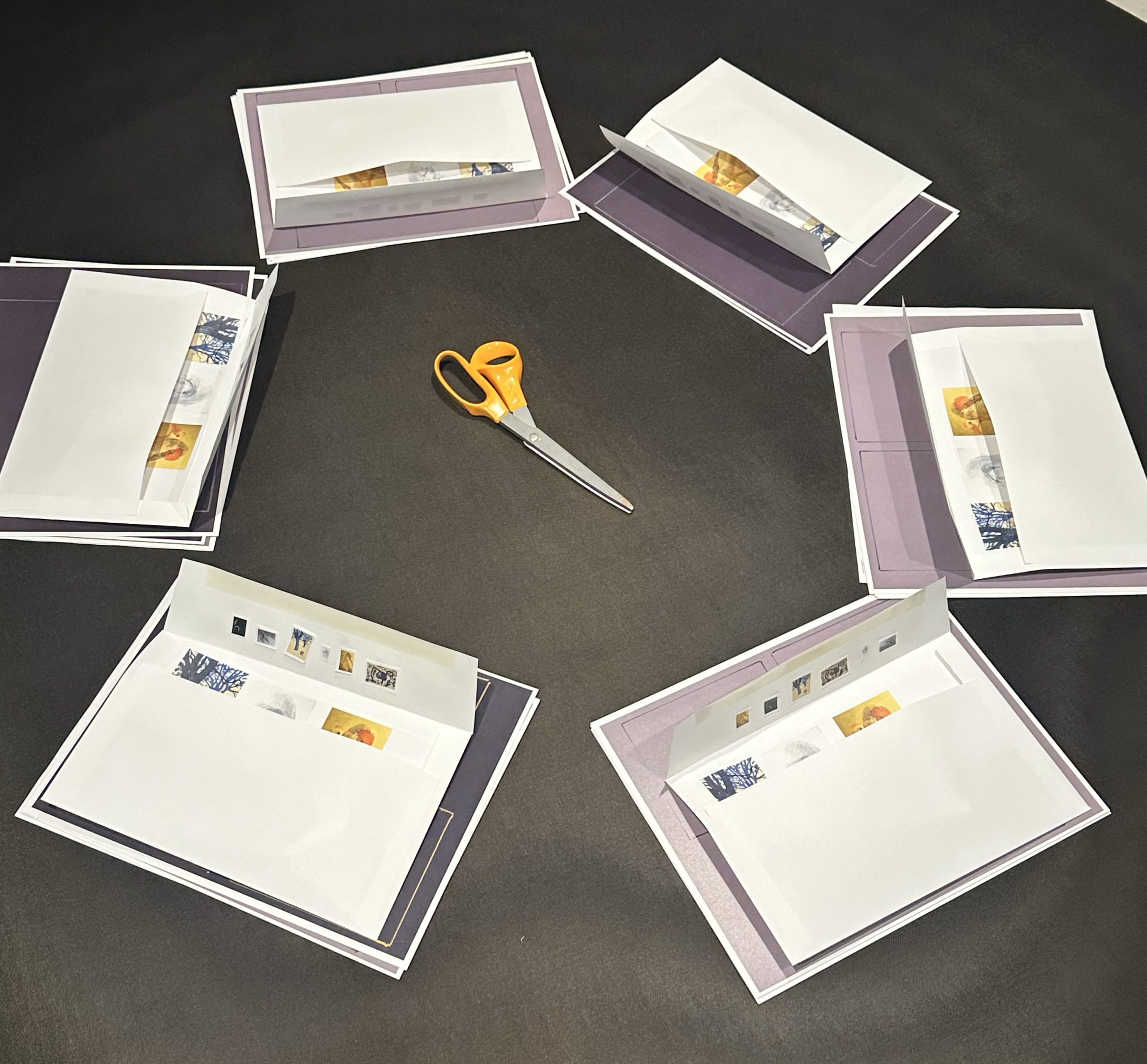 Envelopes with cutout images and colored paper on a table.