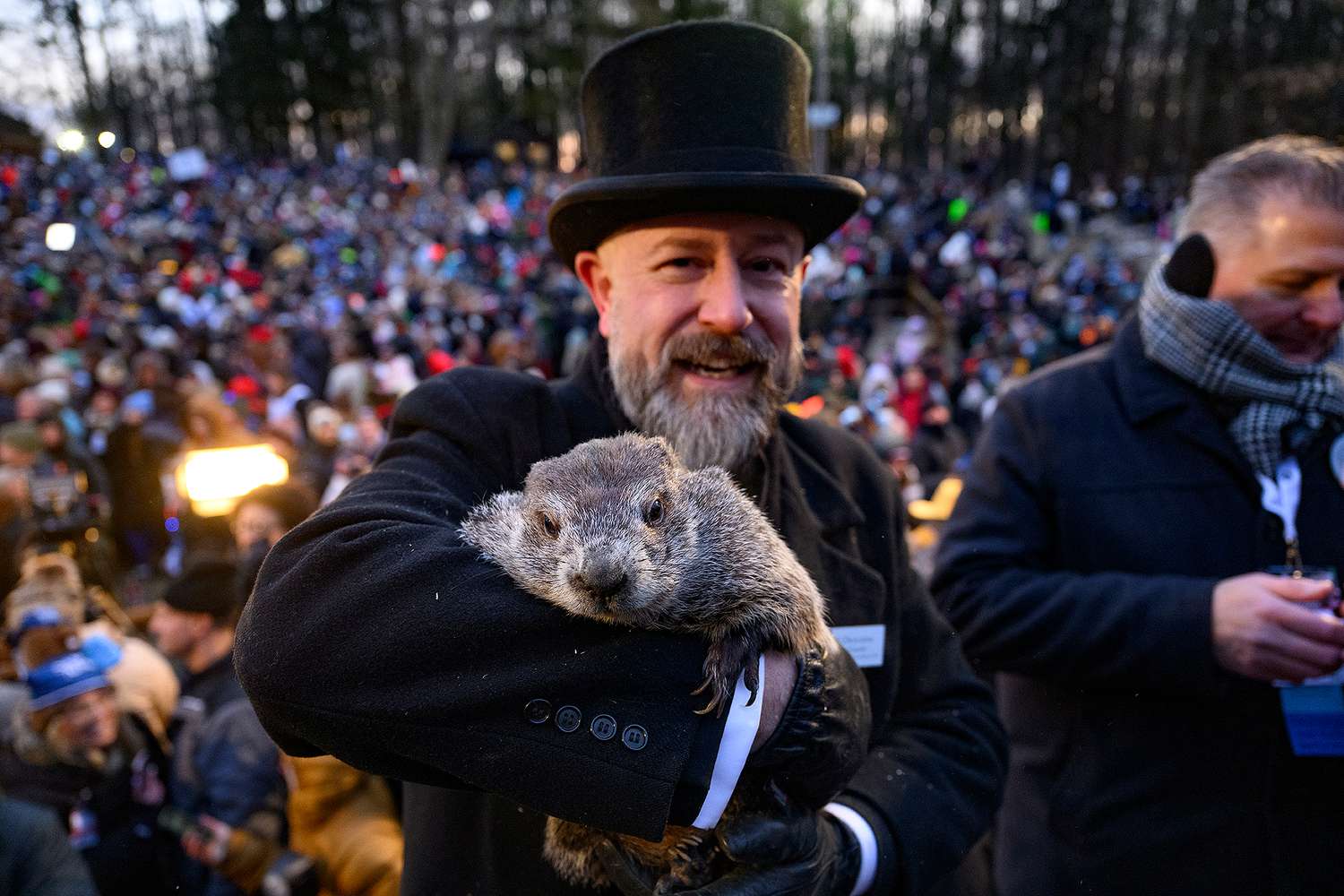 An image from Groundhog Day 2025 in Pennsylvania. The groundhog is being held by a man in a suit and a black top hat. 